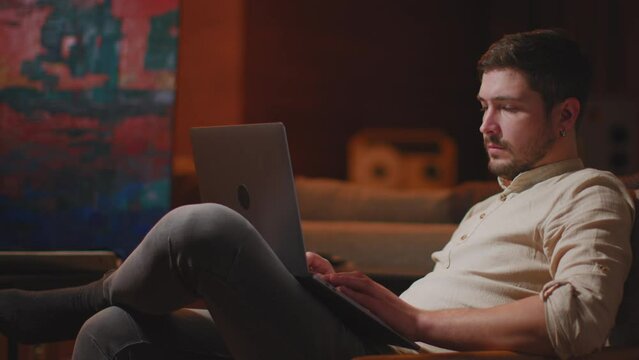 Creative man painter designer working on laptop in art workshop, answer customers, surching inspiration for new project