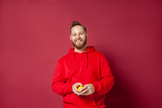 Smiling man with lemon against red background