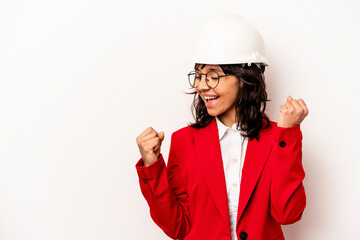 Young architect hispanic woman with helmet isolated on white background raising fist after a victory, winner concept.