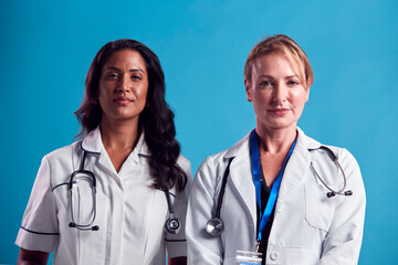 Fototapeta premium Portrait Of Female Doctor And Nurse Wearing White Coat Standing In Front Of Blue Studio Background