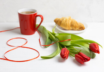 A cup of tea with a croissant, delicate flowers and the number 8. A greeting card for Women's Day on March 8.