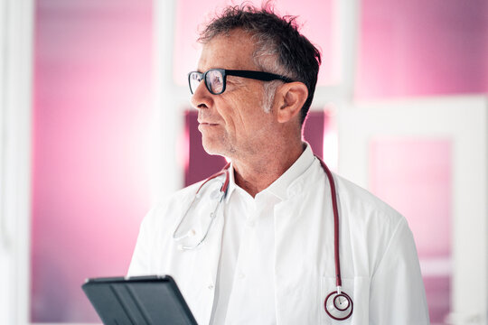 Thoughtful doctor with tablet PC standing in clinic - Powered by Adobe
