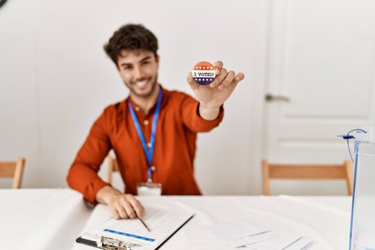 Young hispanic man smiling confident holding badge at electoral college