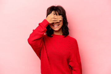 Young hispanic woman isolated on pink background covers eyes with hands, smiles broadly waiting for...