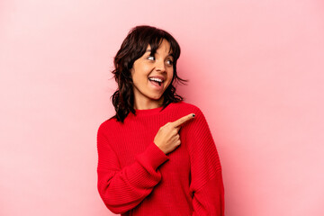 Young hispanic woman isolated on pink background looks aside smiling, cheerful and pleasant.