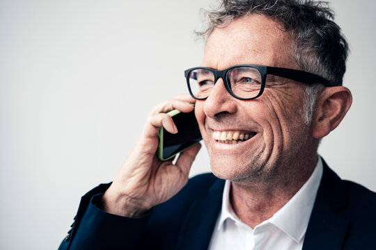 Cheerful businessman talking on smart phone at studio