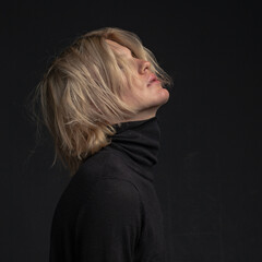 Obraz premium portrait of a young attractive man with blond hair in dark clothes on a dark background