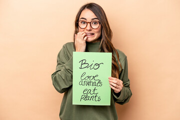 Young caucasian woman holding a bio placard isolated on beige background biting fingernails, nervous and very anxious.