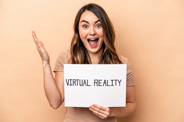 Young caucasian woman holding a virtual reality placard isolated on beige background receiving a pleasant surprise, excited and raising hands.