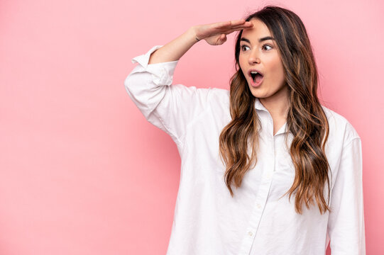 Young caucasian woman isolated on pink background looking far away keeping hand on forehead.