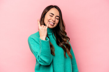 Young caucasian woman isolated on pink background showing rock gesture with fingers