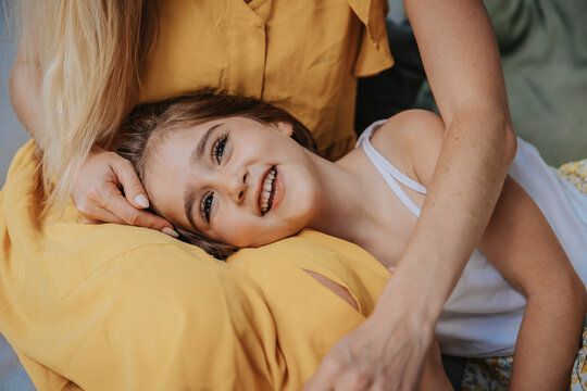Smiling daughter lying on mother's lap at patio