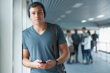 His cellphone is his social network. Shot of a handsome young college student holding a cellphone with friends in the background.