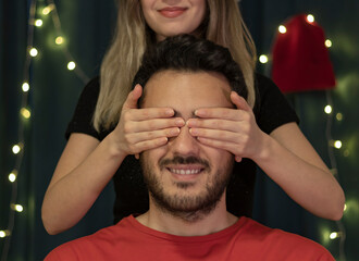 Happy young woman covering her boyfriends eyes from behind. Girls face is not seen in photo. Bokeh...