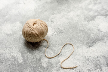 Fototapeta na wymiar A tangle of beige-colored wool threads on a white concrete background