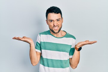 Young hispanic man wearing casual clothes clueless and confused with open arms, no idea concept.
