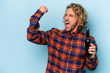 Young caucasian man holding beer isolated on white background raising fist after a victory, winner concept.
