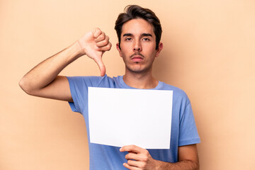 Young caucasian man holding a placard isolated on beige background showing a dislike gesture,...
