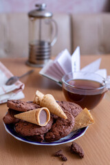 Tea with cookies and waffle tubes, an open book in the background on the table in the interior of the room