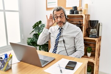 Middle age hispanic business man working at the office wearing operator headset smiling with hand...