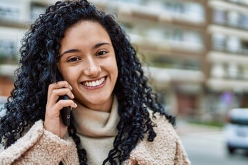 Young hispanic woman smiling confident talking on the smartphone at street