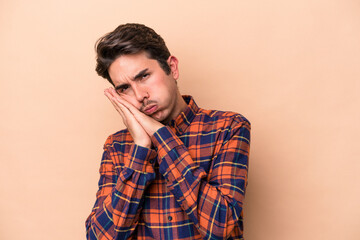 Obraz premium Young caucasian man isolated on beige background yawning showing a tired gesture covering mouth with hand.