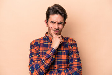 Obraz premium Young caucasian man isolated on beige background unhappy looking in camera with sarcastic expression.