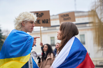 Caucasian woman with Russian flag arguing with caucasian man with Ukrainian flag on street...