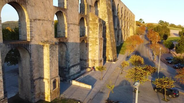Dronie shot of an old aqueduct in Elvas, Portugal with golden hour lighting.