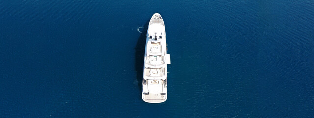 Aerial drone ultra wide top down photo of large yacht with wooden deck anchored in Aegean island...