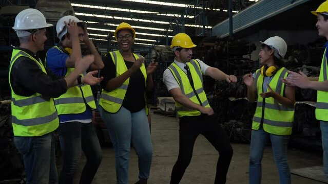 group of happy diversity warehouse worker celebrate to success dancing show and having fun together At break after work in industry factory. funny teamwork of multiethnic colleagues laughing enjoying