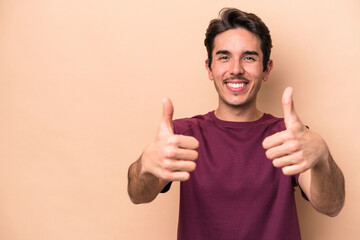 Young caucasian man isolated on beige background smiling and raising thumb up