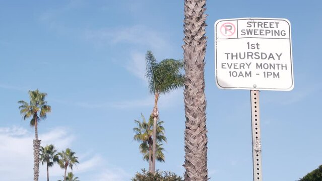 No parking road sign, street sweeping signage, city near Los Angeles, California USA. Traffic shield and cloudy sky. Palm trees. San Diego Ocean Beach.