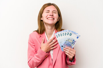 Young business English woman holding banknotes isolated on white background laughs out loudly keeping hand on chest.