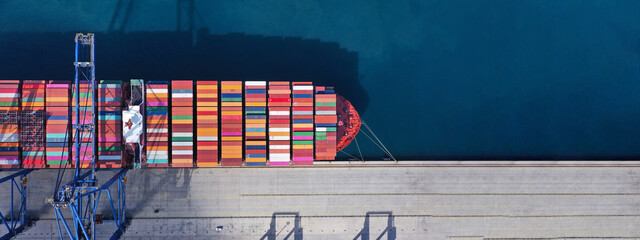 Aerial drone ultra wide top down photo of anchored container ship in loading - unloading in logistics terminal port - obrazy, fototapety, plakaty