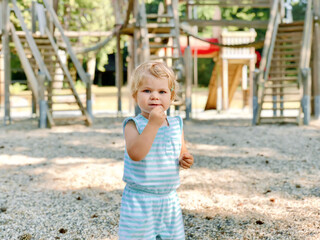 Little toddler girl playing on outdoor playground. Happy toddler child climbing and having fun with summer outdoors activity.