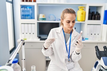 Young blonde woman wearing scientist uniform analysing blood at laboratory