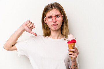 Young English woman holding an ice cream isolated on white background showing a dislike gesture,...