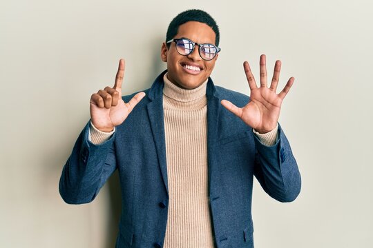 Young handsome hispanic man wearing elegant clothes and glasses showing and pointing up with fingers number seven while smiling confident and happy.