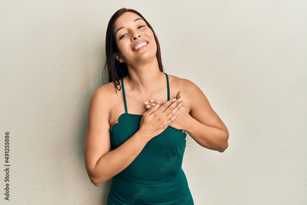 Sticker young latin woman wearing casual clothes smiling with hands on chest with closed eyes and grateful g