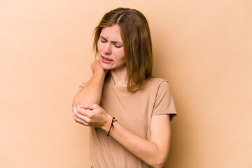 Obraz premium Young English woman isolated on beige background massaging elbow, suffering after a bad movement.