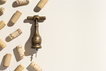 Wine corks and vintage corkscrew on beige background with shadows at sunlight. Minimal style layout with bottle cork, old bottle screw or opener, design concept for wine list, copy space