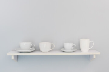 Four white cups on a white shelf