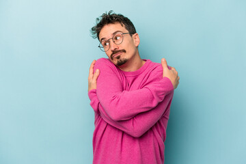 Young caucasian man isolated on blue background hugs, smiling carefree and happy.