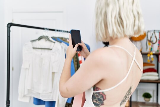 Young caucasian woman make photo to clothes at clothing store