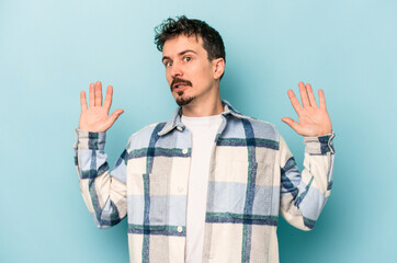 Young caucasian man isolated on blue background being shocked due to an imminent danger
