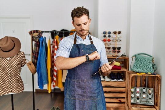 Handsome young man working as manager at retail boutique checking the time on wrist watch, relaxed and confident