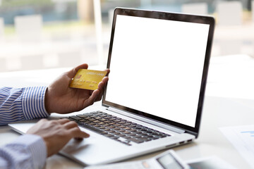 Hand holding credit card working on laptop. Copy space on laptop screen.