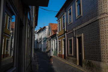 Fototapeta na wymiar A boy on a narrow street residential house with tiles on the facade