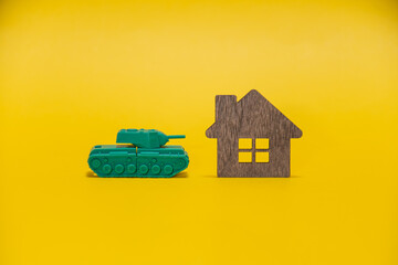 Ivanovo, Russia - 03.03.2022:A miniature of a real tank lies on a wooden house on a yellow...